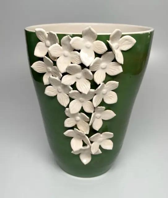 A green vase with white flowers