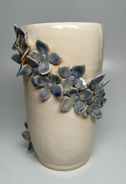 A white vase with blue flowers