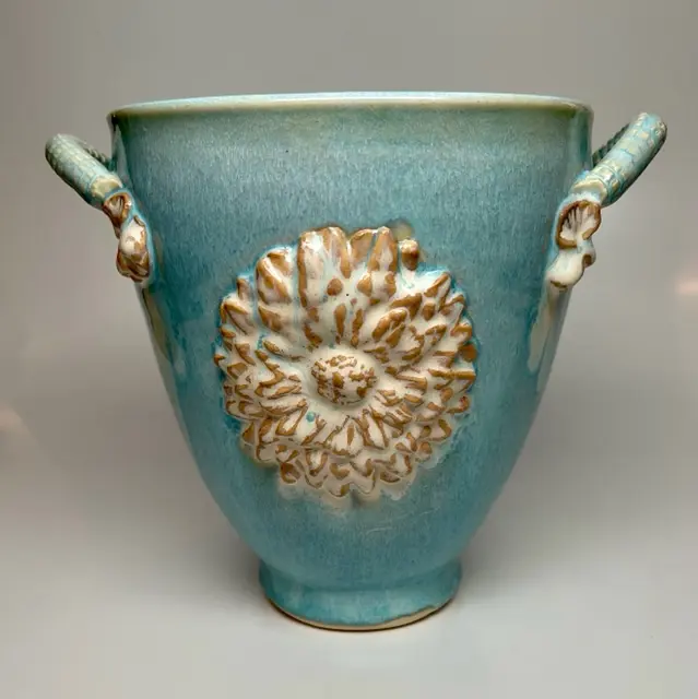 A light blue vase with a flower design